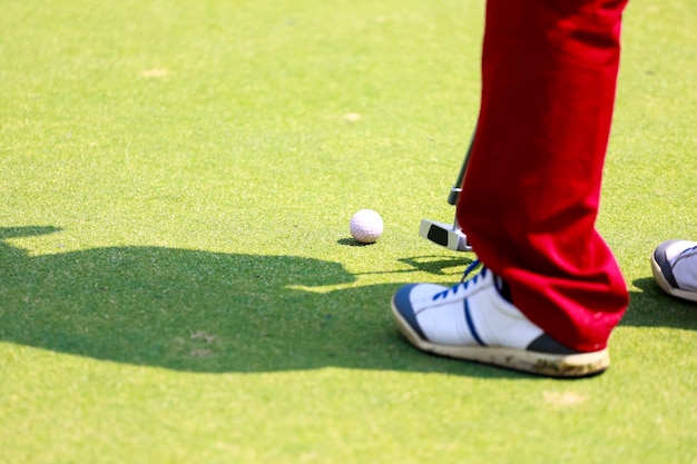 Golfspeler bij de putting green die de bal in een gat slaat