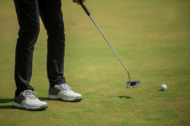 Golfspeler bij het putting green die bal in een gat raakt