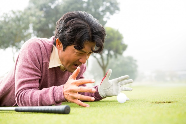 Golfspeler die dichtbij golfbal ligt