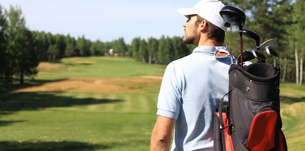 Golfspeler wandelen en draagtas op cursus tijdens golfen in de zomer.