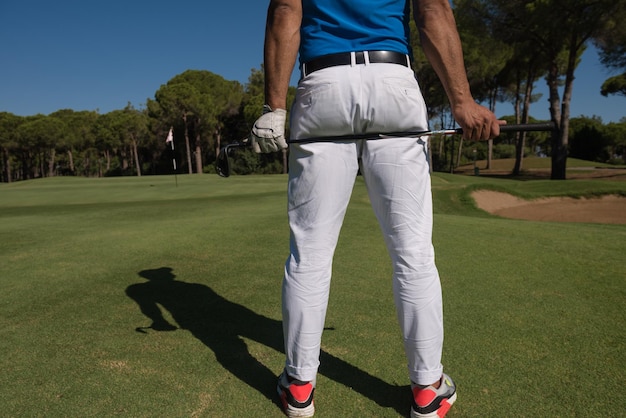 golfspelerhand en bestuurder close-up van achteren met koers op de achtergrond op mooie zonnige dag