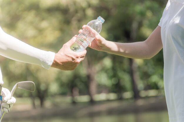 Golfspelers sturen drinkwaterflessen naar vrienden met een wazige zachte natuurachtergrond.