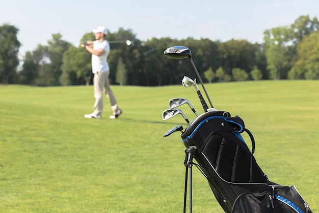 Golfuitrusting Golfclubs in golftas op de voorgrond man die golf speelt op de achtergrond tijdens de zomervakantie