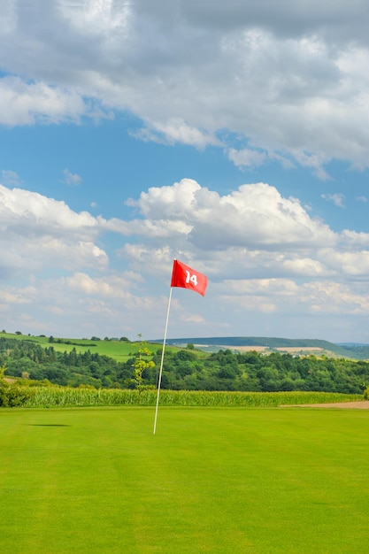 Golfveld met groene gras rode vlag en bewolkte blauwe lucht Golfbaan