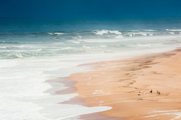 Golven aan de oever van de Atlantische Oceaan in de Algarve, Portugal. Mensen lopen op zandstrand