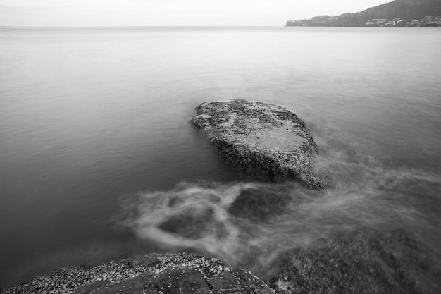 Golven over de rotsen aan de kust in zwart-wit Fotografie met lange belichtingstijd