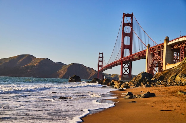 Golven over zandstranden bij de Golden Gate Bridge bij zonsondergang