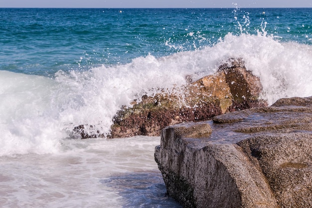 golven slaan tegen de rotsen op het strand in lloret de mar