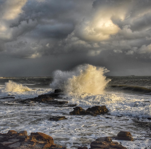 Foto golven spatten op rotsen aan de kust tegen de lucht