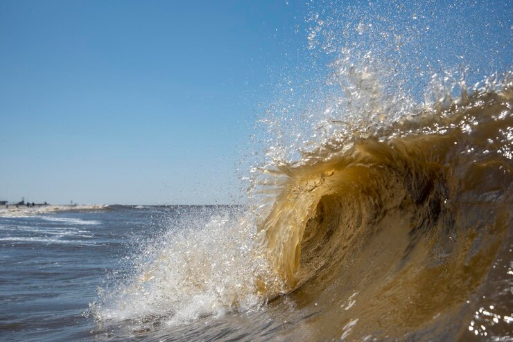 Foto golven spetteren op de kust tegen een heldere hemel.