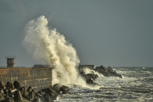 Foto golven spetteren op de kust tegen een heldere hemel.