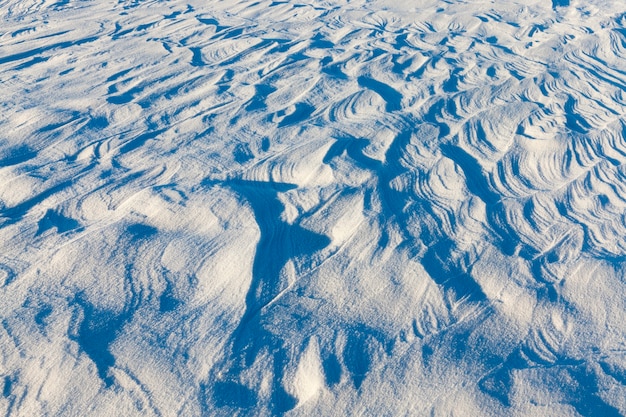 Golvend gestreept oppervlak van sneeuw, gevormde diepe sneeuwlaag, winteraard bij zonnig weer