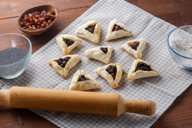 Gomentashash with poppy seeds and prunes freshly baked for the purim holiday on a gray checkered