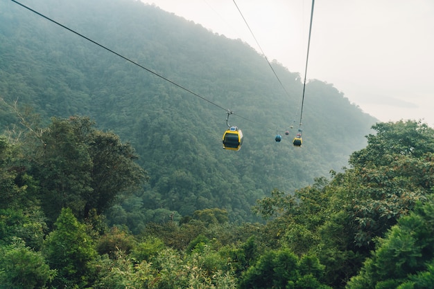 Gondola lifts moving over mountain with green trees in the area of Sun Moon Lake Ropeway