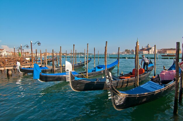 Gondolas moored at grand canal against clear blue sky