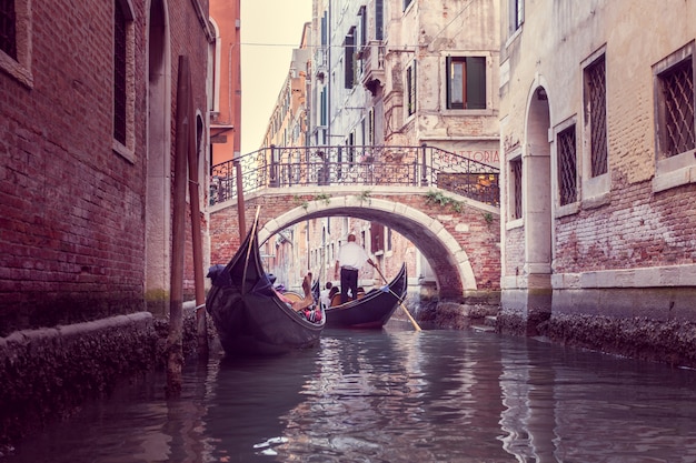 Il gondoliere galleggia su uno stretto canale a venezia