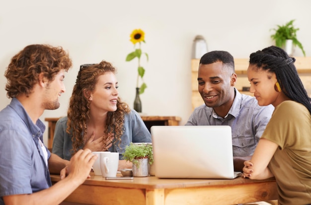 In buona compagnia un gruppo di amici seduti insieme in una caffetteria con un laptop