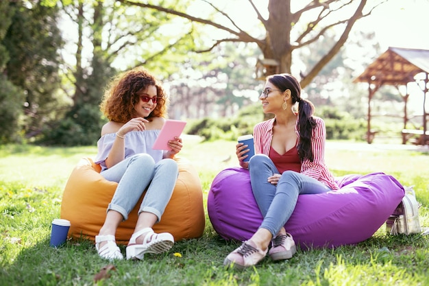 Good day. Inspired young women sitting in the chairs and and relaxing in the open air