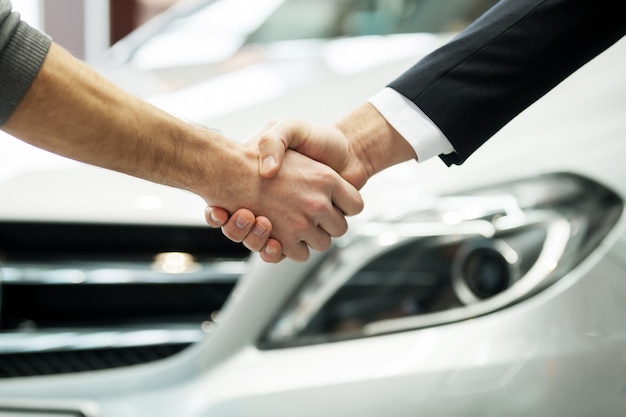 Good deal. Close-up shoot of the hands shaking in front of the car