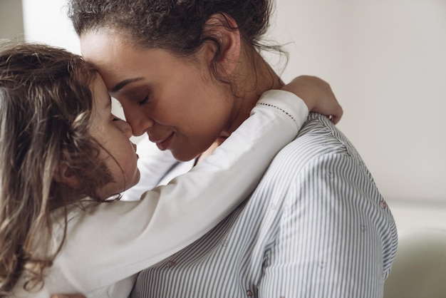 Foto buona famiglia madre e figlia piccola figlia che abbraccia sua madre con un sorriso e gli occhi chiusi a casa