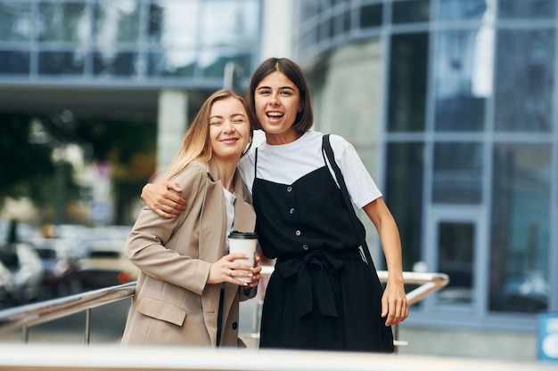 Good friends Women in formal wear is outdoors in the city together