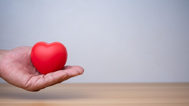 Foto buona salute e concetto di assicurazione assicurazione sanitaria concetto di mano umana che tiene il cuore rosso