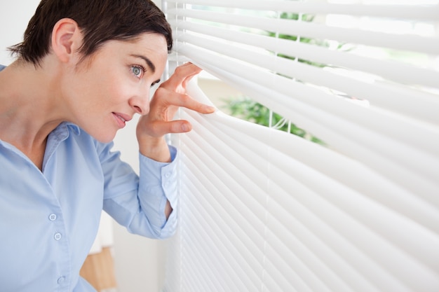 Good-looking brunette woman peeking out a window