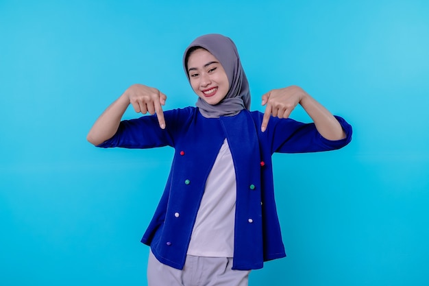 Good looking charismatic young woman with wearing hijab pointing isolated on light blue background