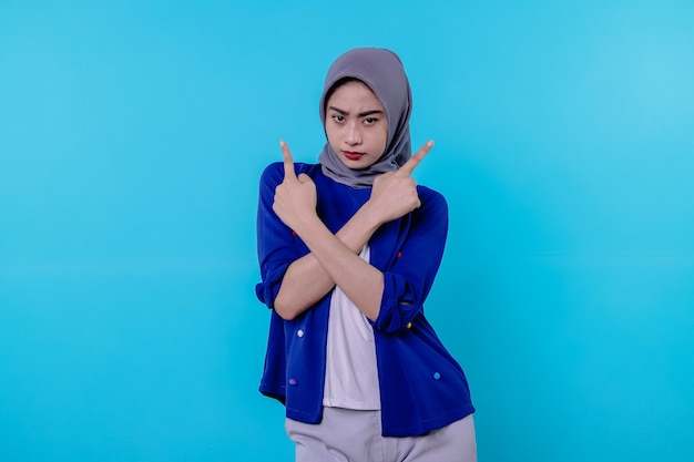 Good looking charismatic young woman with wearing hijab pointing isolated on light blue background
