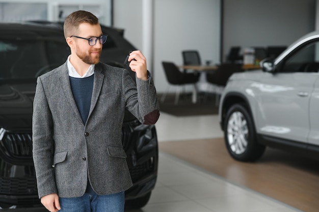 Good looking cheerful and friendly salesman poses in a car salon or showroom