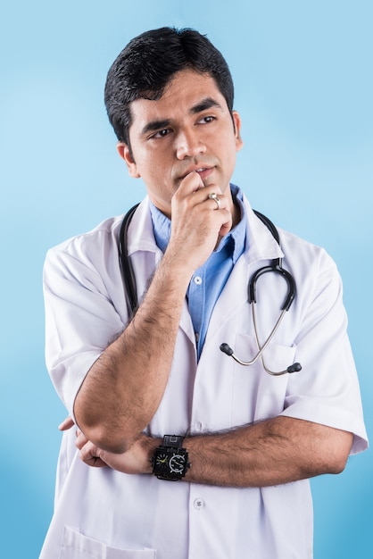 Good looking Indian male doctor with cheerful expressions and hands folded. standing isolated over white background