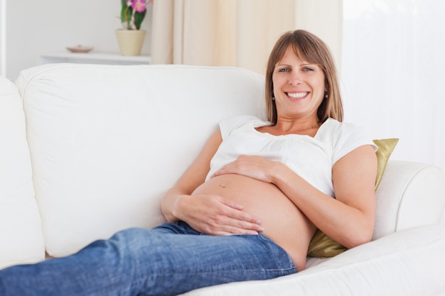 Good looking pregnant woman posing while lying on a sofa