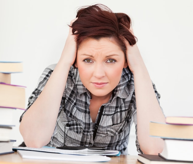 Good looking red-haired girl being upset while studying for an examination