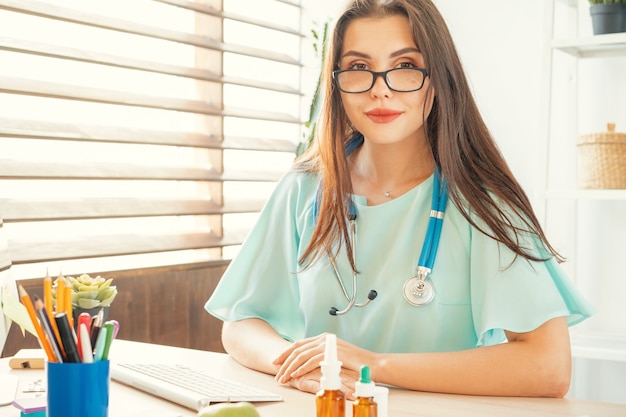 Bella dottoressa seduta al suo tavolo in studio medico