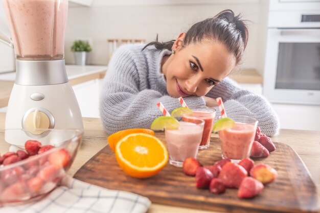 Foto bella donna che si gode i suoi frullati di frutta fatti in casa in cucina.