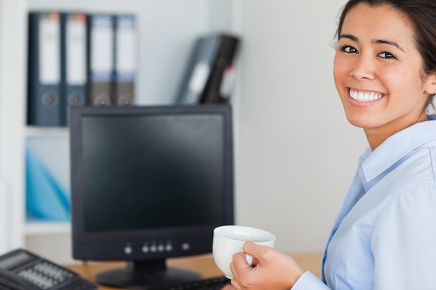 Good looking woman holding a cup of coffee while sitting