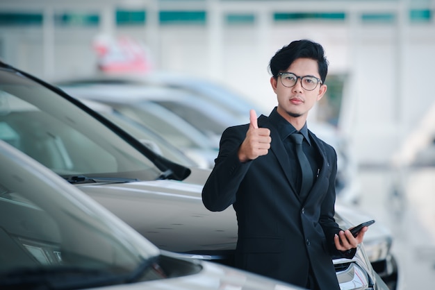 Good looking young business man in asia Show the joy that sales have been completed for the new car showroom.