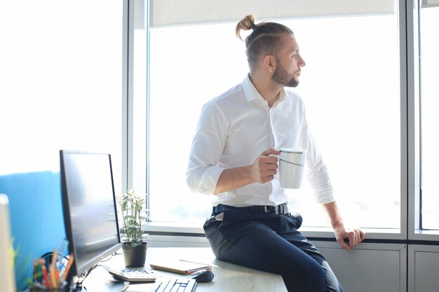 Good looking young business man drinking coffee while sitting in the office.