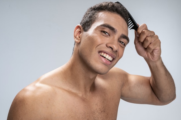 Good-looking young man smiling and doing his hair