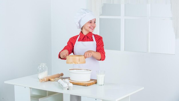 Good mood. bake cookies in kitchen. professional and skilled baker. kid in chef uniform and hat. teen girl preparing dough. making cake by recipe. time to eat. happy child cooking in kitchen.