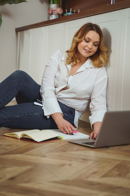 Good mood. Charming girl keeping smile on her face, reading message in the internet