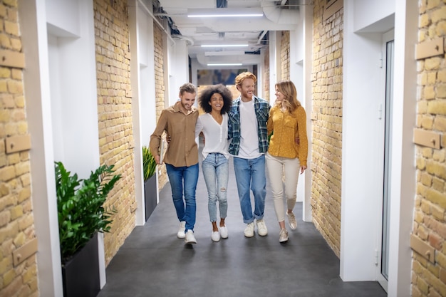 Good mood. Group of smiling young people walking in the corridor