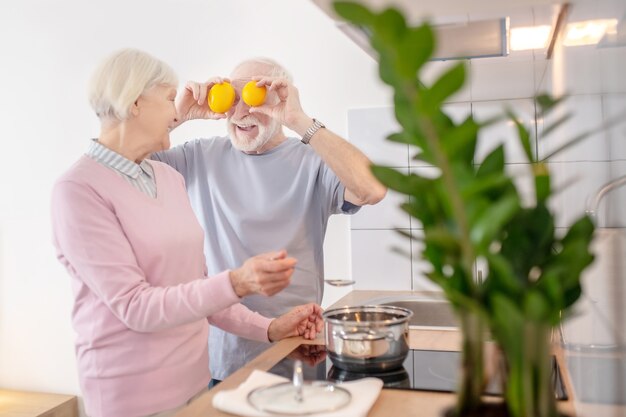 Good mood. Senior couple cooking together in the kitchen and feeling good