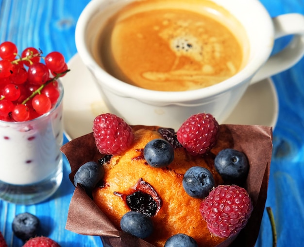 Buongiorno colazione cupcake con frutti di bosco una tazza di caffè e yogurt con ribes rosso