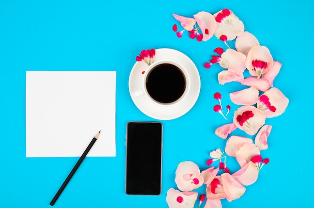 Good morning concept. Flat lay with flowers, smartphone, coffe and clean page