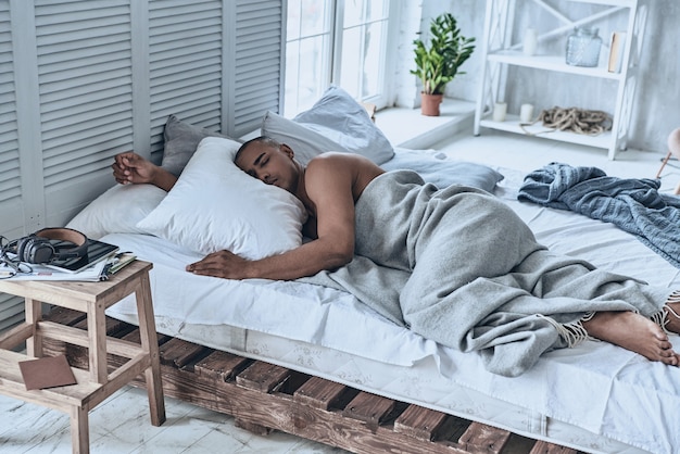 Good nap. Top view of young African man sleeping while lying in the bed at home