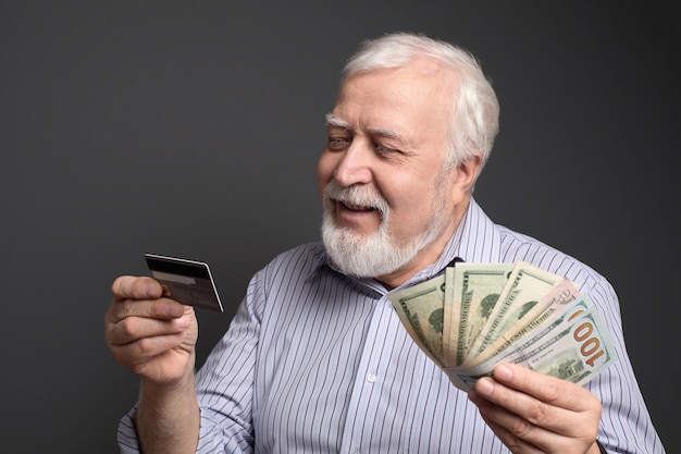 Good-natured smiling man holding a bank card and cash