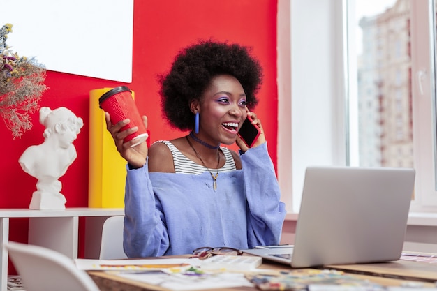 Good news. African-American designer feeling happy hearing good news while speaking by phone