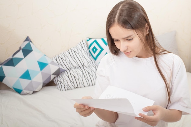 良いニュース女の子は笑顔で家で一枚の紙に手紙を読む