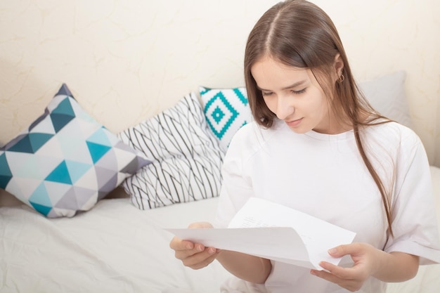 Good news Girl reads a letter on a sheet of paper at home smiling